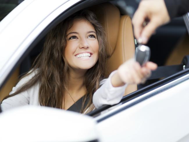 Young woman receiving the keys of her new car