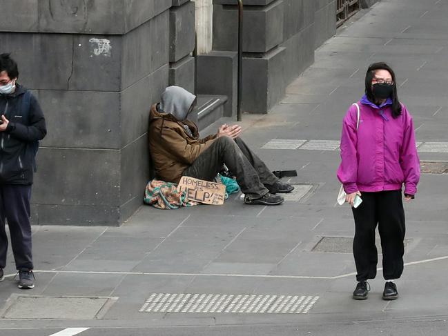 People walk past a homeless man in Melbourne’s Bourke St. Picture: David Crosling