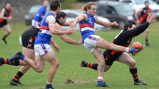 Mornington’s Ryan Odell boots his team forward as Frankston Bomber Waide Symes tries to smother the ball. Picture: Chris Eastman