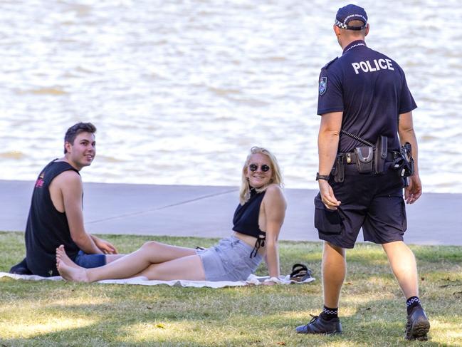 Police speak with a couple at New Farm Park yesterday. Picture: Richard Walker/AAP