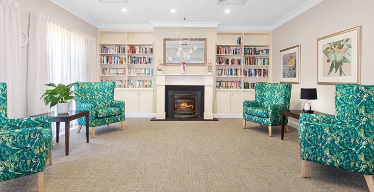 Reading a book by the fireplace is a cosy way to spend time at Estia Health. Picture: estiahealth.com.au