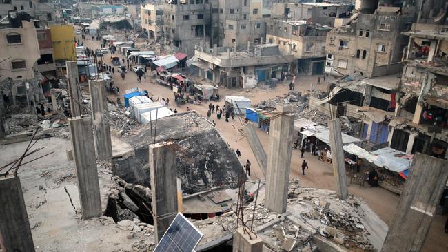 People walk past stalls selling goods amid the rubble of buildings destroyed during previous Israeli strikes, in Khan Yunis in the southern Gaza Strip on January 15. Picture: AFP