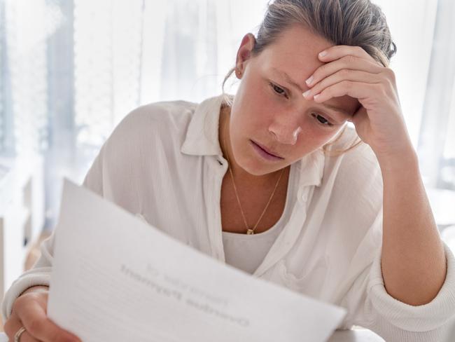 MONEY ISTOCK -  Woman looking worried holding paperwork at home. She is reading a financial bill or a letter with bad news. She looks very stressed and upset. There is a laptop computer on the table Picture: Istock