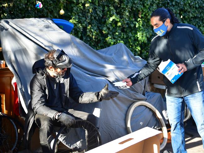 A volunteer offers a face mask to a homeless man in Venice, California. Picture: AFP