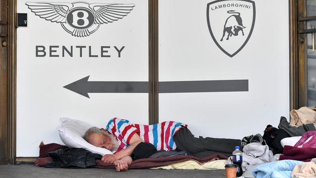 A homeless man sleeps in front of a luxury auto dealership in San Francisco, California. Picture: Josh Edelson/AFP