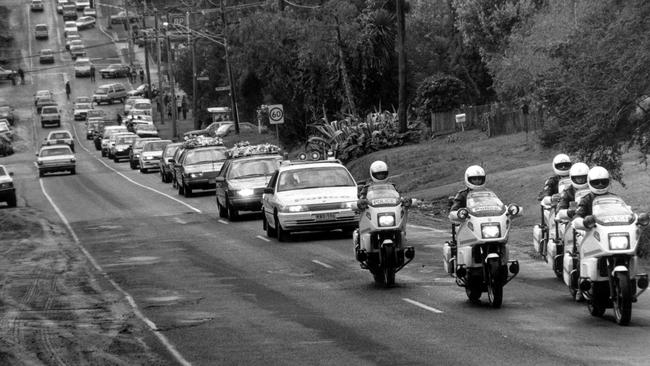 Police motorcycle riders and cars follow Karmein’s funeral cortege along Thompson Rd in Bulleen.