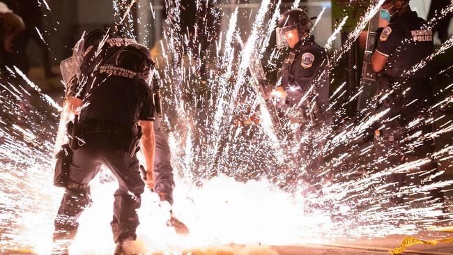 A firecracker thrown by protesters explodes under police one block from the White House. Picture: AFP