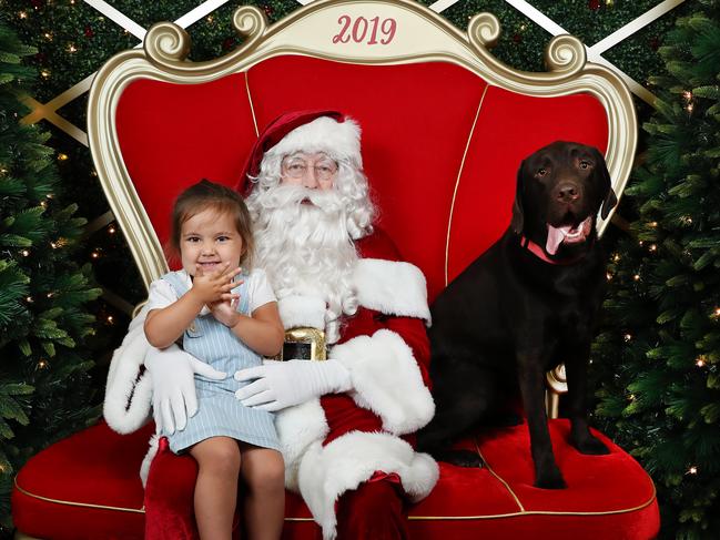 Milla, 2, sits on Santa’s lap with her labrador Bently nearby. Picture: Rohan Kelly