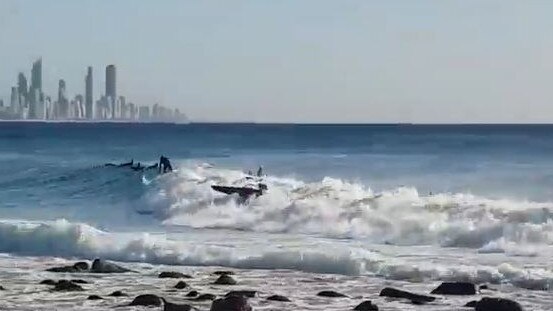 Surfers duck-dive to avoid the careening contraption at Burleigh on the Gold Coast. Picture: Cameron Burke