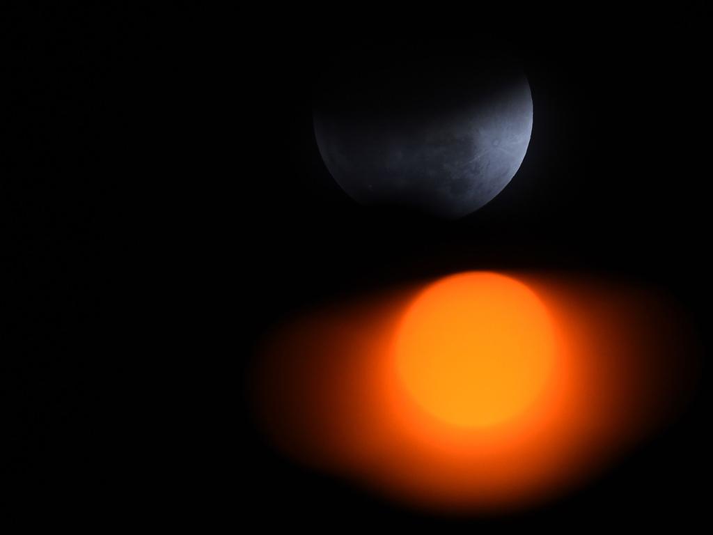 The moon is seen with a street light during a lunar eclipse, referred to as the “super blue blood moon”, in New Delhi on January 31, 2018. Skywatchers were hoping for a rare lunar eclipse that combines three unusual events -- a blue moon, a super moon and a total eclipse -- which was to make for a large crimson moon viewable in many corners of the globe. Picture: AFP