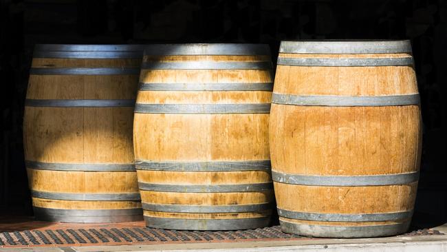 Three wooden barrels with metal straps, dark background with copy space, full frame horizontal composition; Australian exports generic