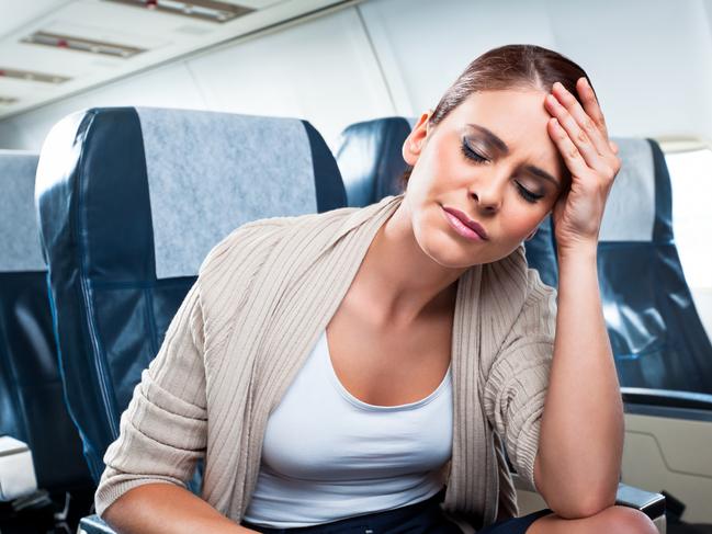 A young woman sitting on an airplane and suffering from headache.