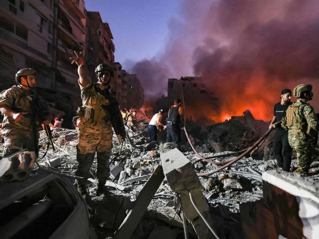 Lebanese army soldiers gather over the rubble of a levelled buildings as people flight the flames, following Israeli air strikes in the Haret Hreik neighbourhood of Beirut's southern suburbs on September 27, 2024. A source close to Hezbollah said the massive Israeli strikes on Beirut's southern suburbs flattened six buildings. (Photo by Ibrahim AMRO / AFP)