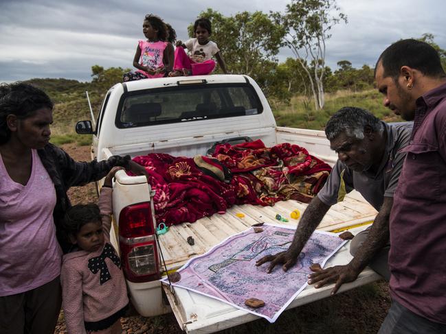 Norm Frank Jupurrurla, his wife Serena Morton Nabanunga and Gus Fitzgerald, an Alice Springs tradesman who is volunteering his time and expertise, survey a satellite image of the block of land where the first three homes of the Wilya Janta (Standing Strong) Housing Collaboration will be built. Frank and other local elders are collaborating with architects and tradesmen from around Australia. Picture: Andrew Quilty/Climate Council