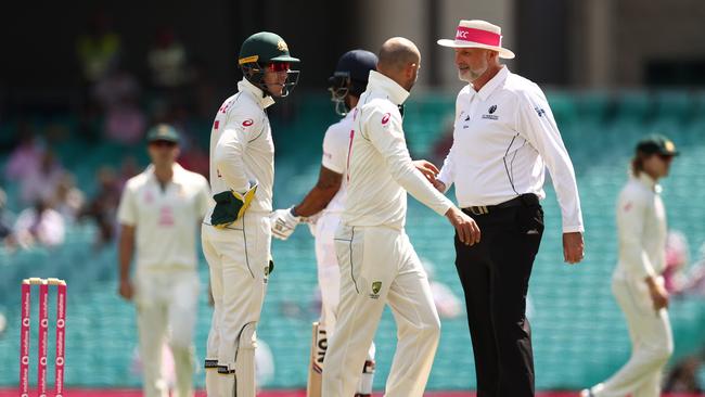 Tim Paine, left, and Nathan Lyon talk to umpire Paul Wilson over a DRS referral