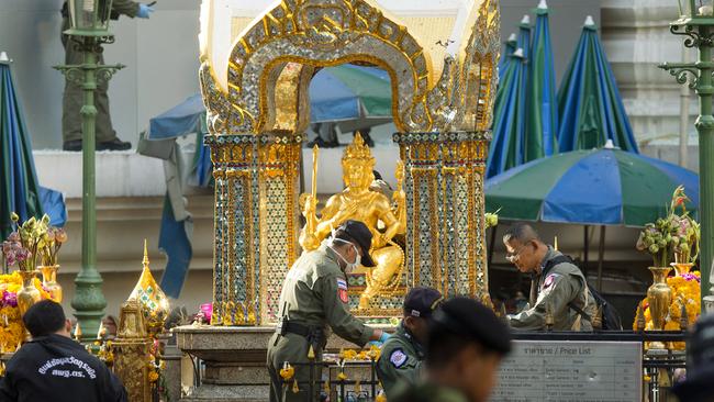 Police investigators work near the statue of Phra Phrom, which is the Thai interpretation of the Hindu god Brahma, at the Erawan Shrine the morning after an explosion in Bangkok, Thailand, Tuesday, Aug. 18, 2015. A bomb exploded Monday within a central Bangkok shrine that is among the city's most popular tourist spots, killing a number of people and injuring others, police said. (AP Photo/Mark Baker)