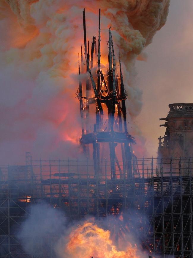 The steeple engulfed in flames collapses as the roof of the Notre-Dame de Paris Cathedral burns on April 15, 2019 in Paris. - A colossal fire swept through the famed Notre-Dame Cathedral in central Paris on April 15, 2019, causing a spire to collapse and raising fears over the future of the nearly millenium old building and its precious artworks. The fire, which began in the early evening, sent flames and huge clouds of grey smoke billowing into the Paris sky as stunned Parisians and tourists watched on in sheer horror. (Photo by Geoffroy VAN DER HASSELT / AFP)