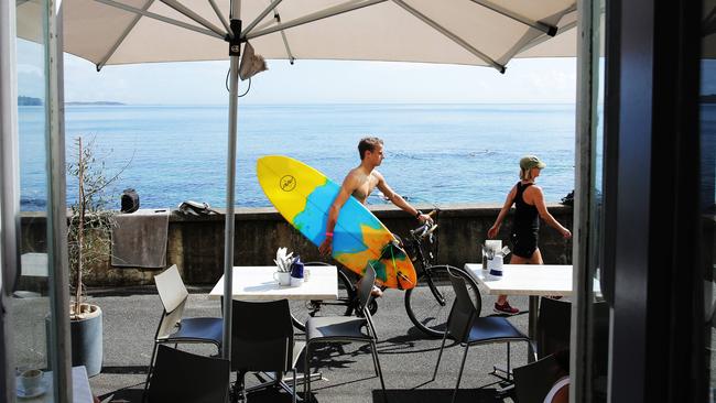 A cyclist with surfboard passes The Bower restaurant Manly in happier times. Picture: Braden Fastier