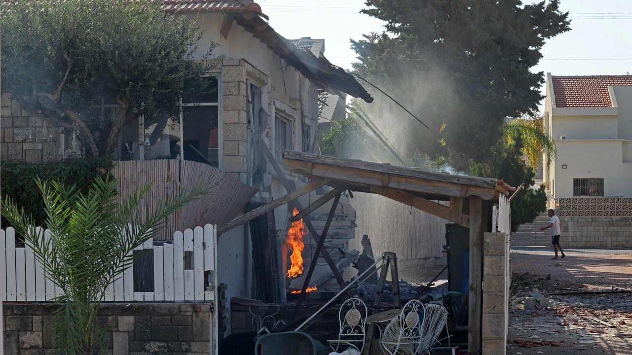 A man runs for covers as fire rages in a house in the southern Israeli city of Ashkelon. Picture: AFP