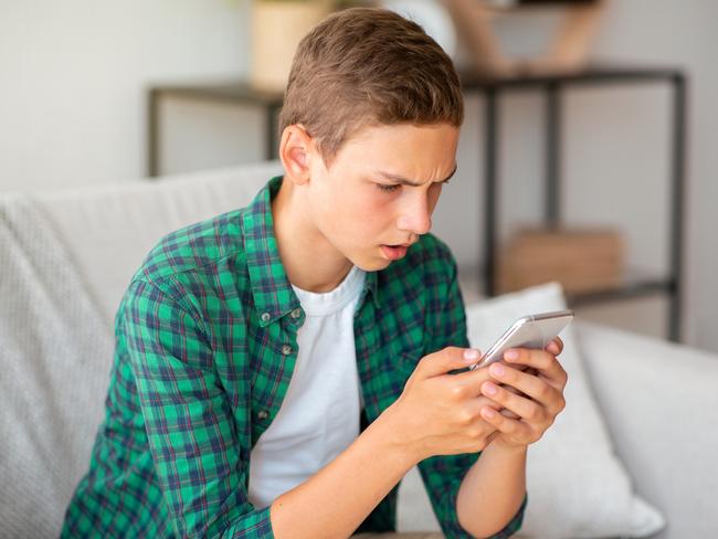 Angry teenager looking at smartphone screen, home interior, copy space  istock image