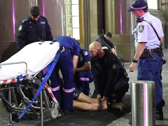 An extremely aggresive man, thought to be under the influence of methamphetamine is finally restrained to a stretcher after a group of up to 10 NSW Police and ambulance officers struggled to subdue him. Picture: Gordon McComiskie