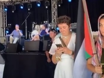 A screenshot of footage from the Woodford Folk Festival, showing Tony Burke (back centre, on the stage) in a Q&amp;A. Pro-Palestine protesters stand in front of the stage. Picture: YouTube