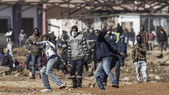 Rioters hurl rocks at police near a looted shopping centre in Vosloorus, South Africa. Picture: AFP