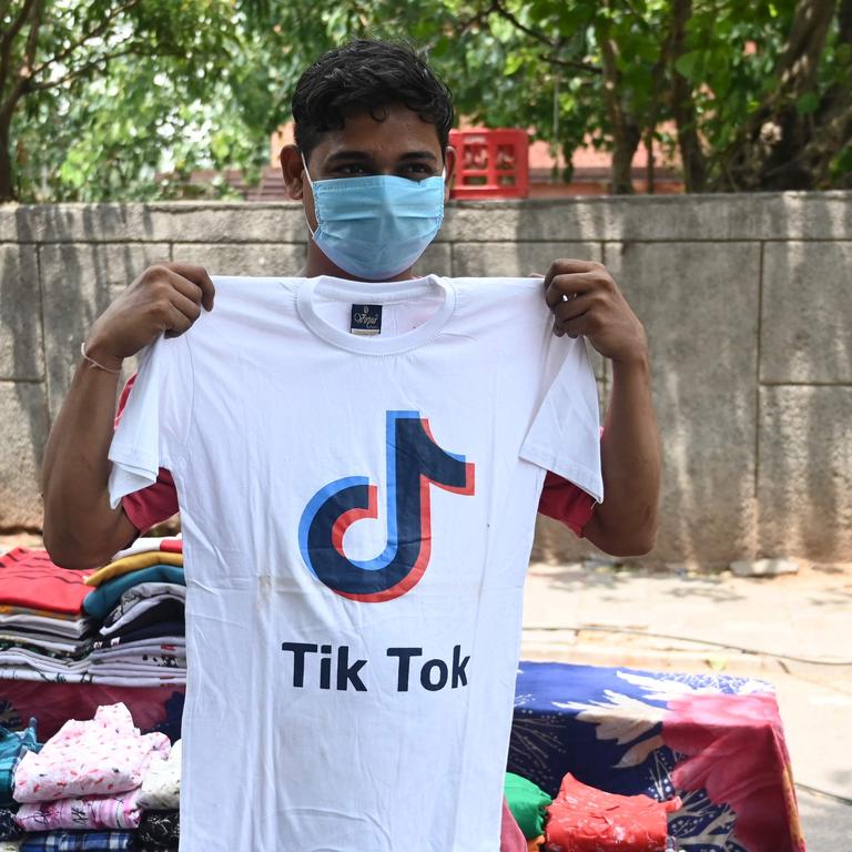 A street vendor holds up a shirt with a TikTok logo in New Delhi, India — where the app was recently banned. Picture: Sajjad Hussain/AFP