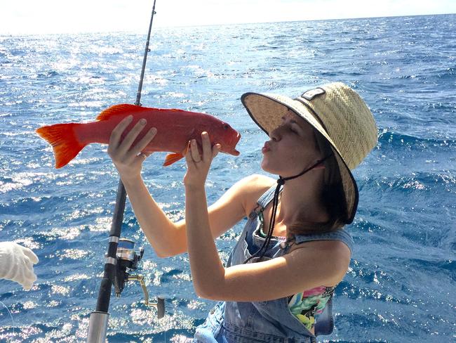 Lucy Birrell whispering to a coral trout she caught recently with Cairns Reef Fishing.