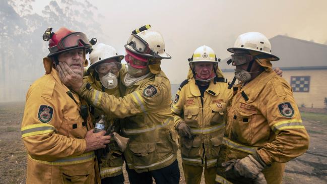 Bawley Point RFS captain Dave Sharpe (red helmet) was overcome with emotion as his colleagues helped him extinguish a blaze surrounding his home. Picture Gary Ramage