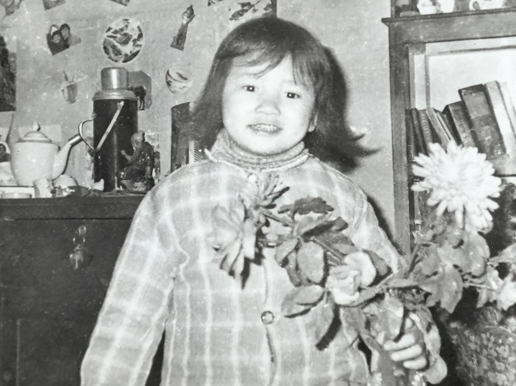 A future impossible to imagine … Cheng Lei aged four, holding plastic flowers at her family home in Yueyang, rural China. Despite growing up in near-poverty, she was a happy child.