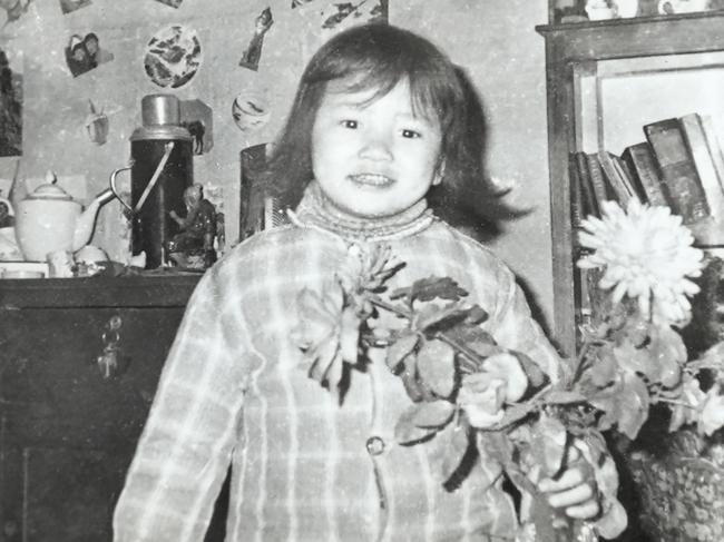 A future impossible to imagine … Cheng Lei aged four, holding plastic flowers at her family home in Yueyang, rural China. Despite growing up in near-poverty, she was a happy child.