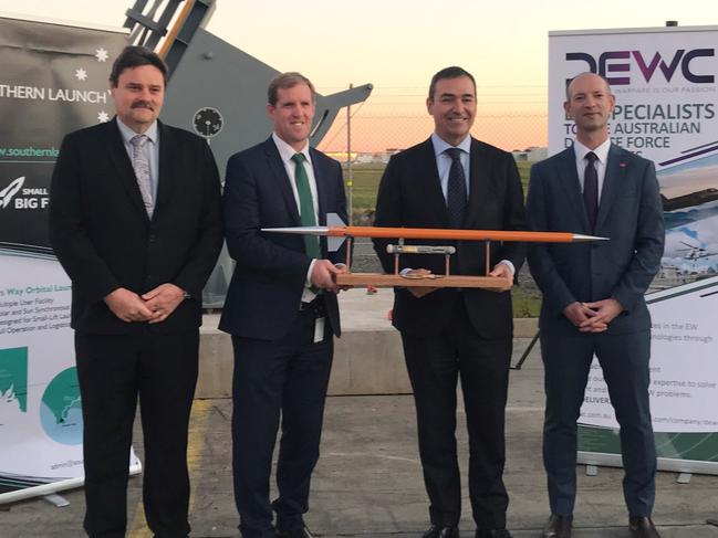 (L-R) Ian Spencer, DEWC Systems CEO; Minister Stephen Patterson MP, Minister for Trade and Investment and SA Premier Steven Marshall holding DEWC System’s payload DEWC-SP1 & Lloyd Damp, Southern Launch CEO. They are posing behind the rocket pedestal that will be used for the launch