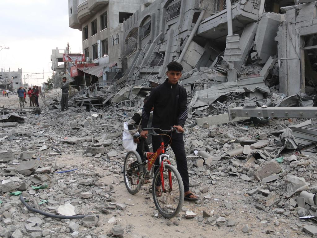 A Palestinian youth pushes his bicycle amid the rubble following Israeli strikes in Nuseirat refugee camp in the central Gaza Strip, on November 1, 2024.