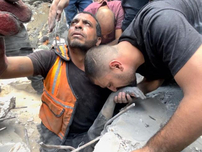 Anadolu Agency photojournalist Ali Jadallah (R), kisses the hand of his brother, who died in Israeli air strike in the Sheikh Radwan district of Gaza City. Picture: Mustafa Hassona/Anadolu via Getty Images