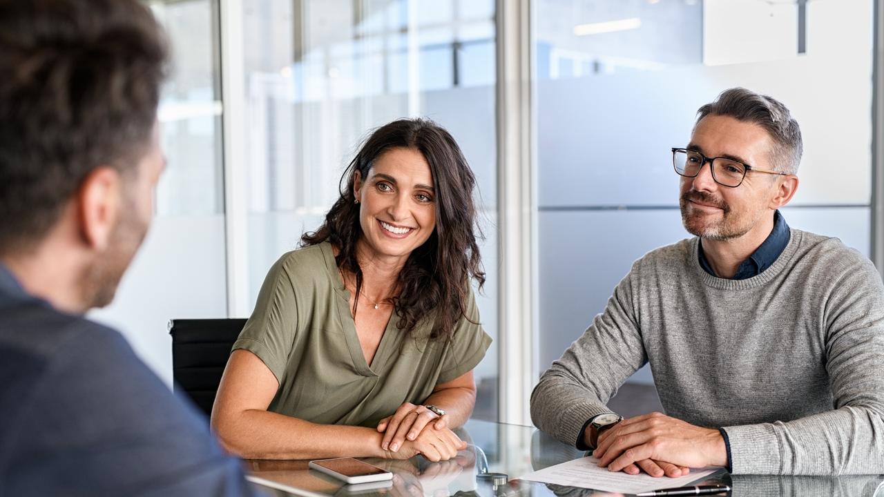 Smiling mature couple meeting with bank manager for investment. Beautiful mid adult woman with husband listening to businessman during meeting in conference room in modern office. Happy middle aged couple meeting loan advisor to buy a new home. Financial planning, advice generic