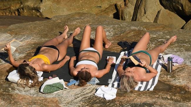 How not to social distance: Sunbakers on the rocks at Mackenzies Bay in Sydney. People now flouting social distancing, quarantine and isolation order face fines of up to $11,000. Picture: AAP