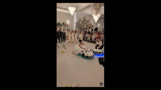 Bride and groom drift into wedding reception in electric toy cars