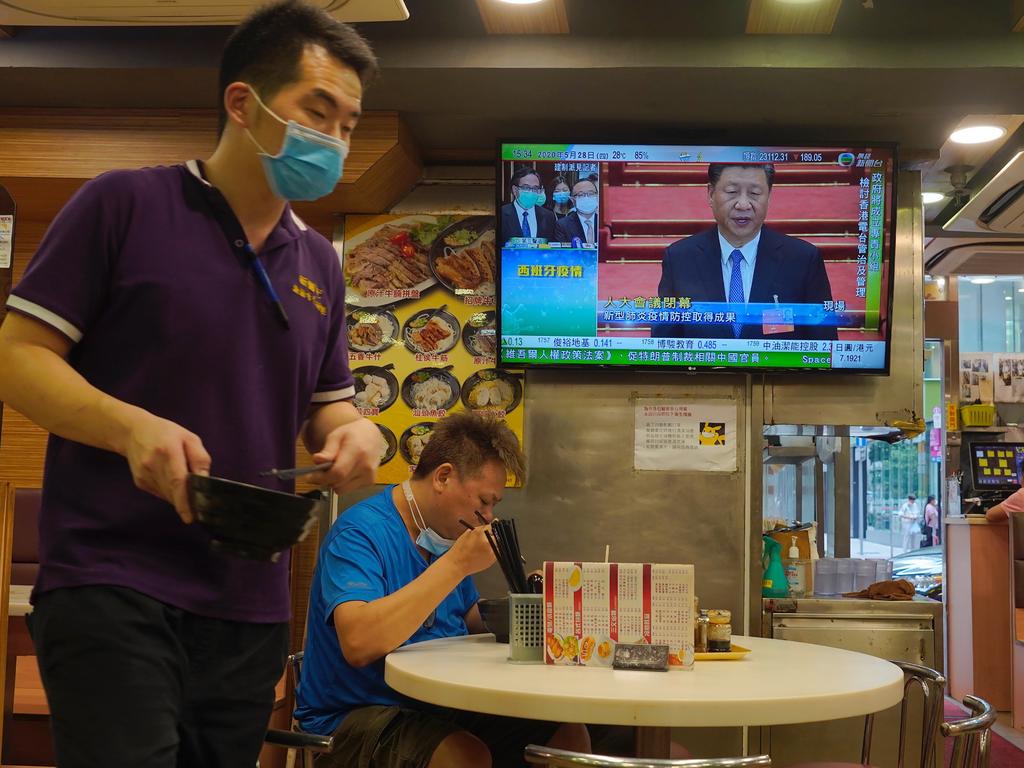 A man has lunch beneath a television showing live telecast of Chinese President Xi Jinping at the closing session of the National People's Congress, Picture: Vincent Yu/AP