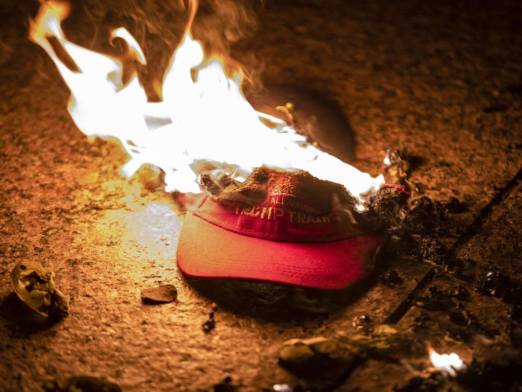 Members of an Antifa group burn a Trump Train hat prior to clashes with a group of Proud Boys following the Million MAGA March. Picture: AFP