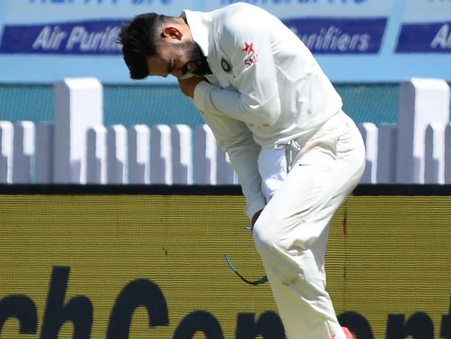 Virat Kohli (R) holds his shoulder after he was injured while fielding during the first day of the third Test cricket match between India and Australia.