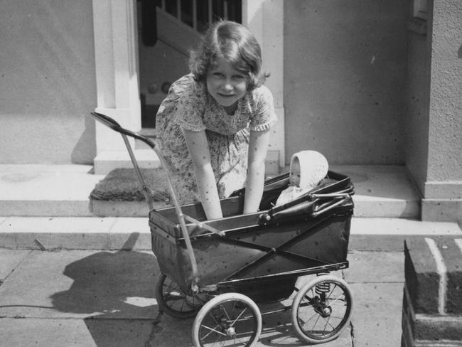 Princess Elizabeth playing with a toy pram outside the Welsh House, a miniature house presented to Princess Elizabeth and Princess Margaret by the people of Wales in the grounds of the Royal Lodge, Windsor. Picture: Central Press/Getty Images