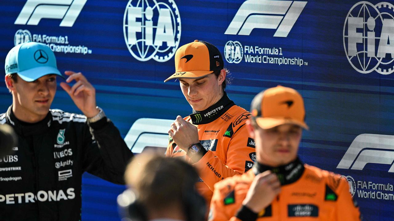 Piastri (centre) looks on after taking pole, with Russell (left) second and Lando Norris (right) third. (Photo by Hector RETAMAL / AFP)