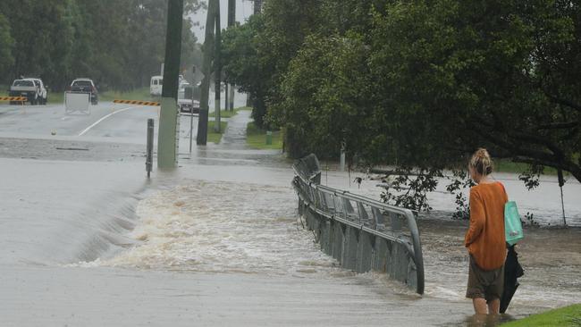 A woman viewsfloodwater on a Helensvale street. Picture: Glenn Hampson.
