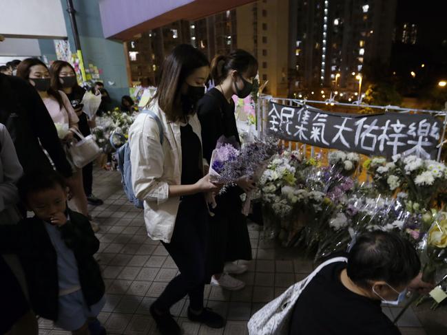 Protesters lay flowers near a banner which reads "From all of us – God bless Chow Tsz-Lok" to pay homage to Chow at the site where he fell in Hong Kong. Picture: AP