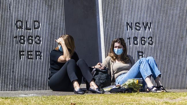 An emotional scene at the Queensland-NSW border at Coolangatta, where two women, separated by border restrictions, hold hands. Picture: NIGEL HALLETT