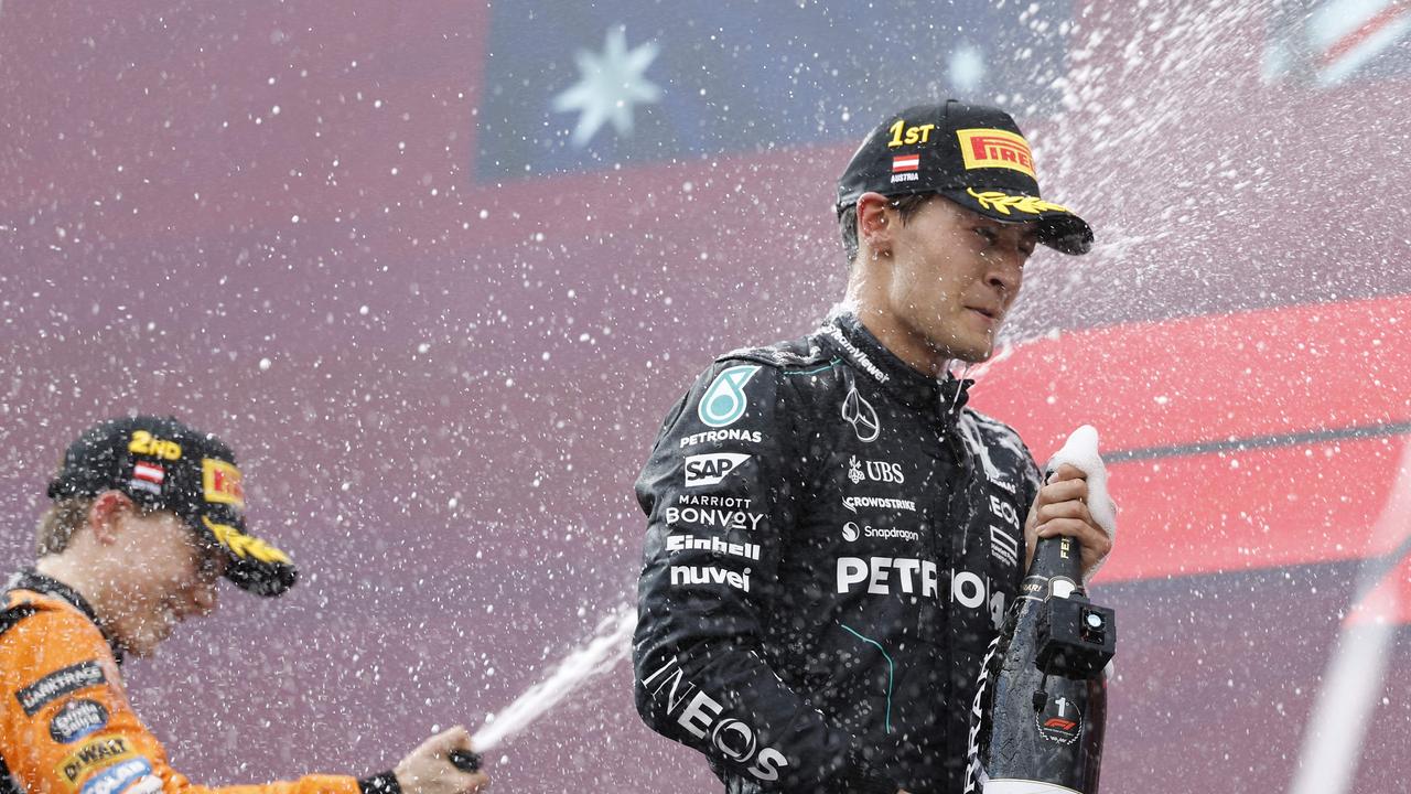 Winner Mercedes' British driver George Russell (R) and McLaren's Australian driver Oscar Piastri celebrate on the podium after the Formula One Austrian Grand Prix on the Red Bull Ring race track in Spielberg, Austria, on June 30, 2024. (Photo by ERWIN SCHERIAU / APA / AFP) / Austria OUT