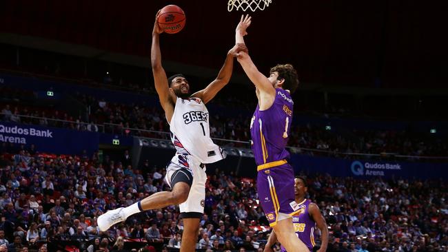 Obi Kyei of the 36ers slam dunks under pressure from Jordan Hunter of the Kings.