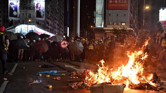 TOPSHOT - Protesters stand near burning items during a protest on Hennessy Road, in Hong Kong on August 31, 2019, in the latest opposition to a planned extradition law that has since morphed into a wider call for democratic rights in the semi-autonomous city. - Chaos engulfed Hong Kong's financial heart on August 31 as police fired tear gas and water cannon at petrol bomb-throwing protesters, who defied a ban on rallying -- and mounting threats from China -- to take to the streets for a 13th straight weekend. (Photo by Lillian SUWANRUMPHA / AFP)