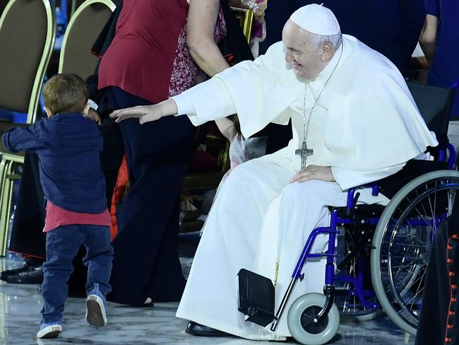 Pope Francis reaches out to a two-year-old child playing onstage during an audience as part of the Festival of Families in The Vatican. Picture: AFP